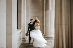 a bride and groom are dancing in an old building with columns on either side of them