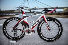 a white and red bike parked on the side of a road next to a bridge