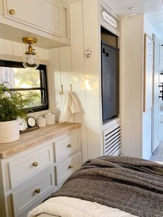 a bed in a room with white cupboards and drawers next to an open window