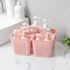 a pink bathroom caddy with soap and lotion in it on a marble countertop