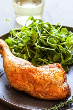 a close up of a plate of food with meat and greens on the side next to a glass of water