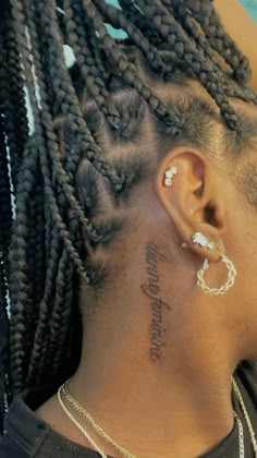 the back of a woman's head with braids and tattoos on her neck