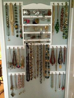 a closet filled with lots of necklaces and bracelets hanging on the wall next to a door