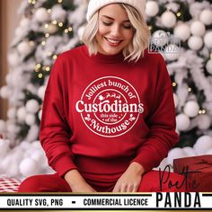 a woman sitting in front of a christmas tree wearing a red sweatshirt with the words custodians on it