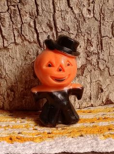 an orange toy with a top hat on it's head sitting next to a tree