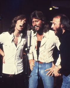 three men standing next to each other in front of a microphone