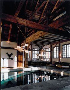 an indoor swimming pool in the middle of a room with large windows and wooden beams