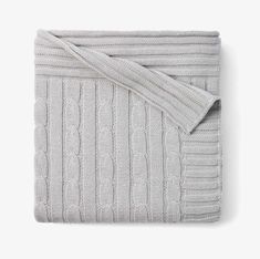 the grey cable knit blanket is folded up