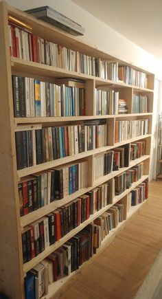 a bookshelf filled with lots of books on top of a hard wood floor