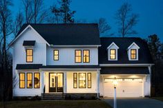 a white two story house with lights on at night