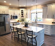 a large kitchen with white cabinets and stainless steel appliances