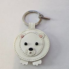 a white key chain with a bear face on it's front and back sides