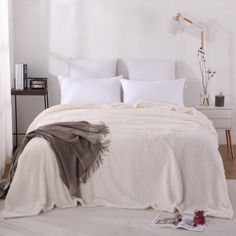 a bed with white sheets and pillows in a room