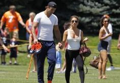 a man and woman holding hands while walking in the grass with other people behind them