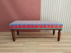 a bench sitting on top of a hard wood floor next to a pink and white wall