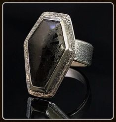 This beautiful gothic coffin design ring has a unique type of tile material that has little chips of shiny black glass encased in a semi-flat binder to create a durable and dynamic looking cabochon. Hand crafted and made to order, these wonderful rings can be customized. Just send us a message and we can work out the details to create a personal, one-of-a-kind piece of jewelry for you. All of our jewelry is completely hand fabricated in-house so we can build it to your specifications. Black Jewelry With Custom Hardware As Gift, Custom Black Jewelry With Hardware For Gift, Unique Black Rectangular Jewelry, Coffin Design, Gothic Coffin, Wedding Ring Finger, Tile Material, Coffin Ring, Blue Goldstone