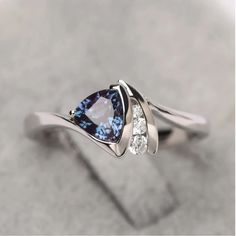 a blue and white diamond ring with two diamonds on it's sides, sitting on top of a gray surface