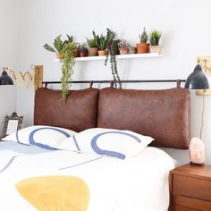 a bed with two plants on the headboard and one plant hanging over it's head