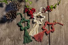 christmas ornaments are laid out on a wooden surface with pine cones, holly and berries