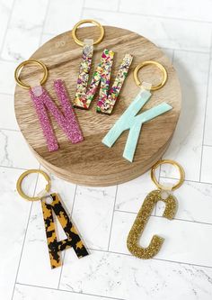 three keychains are sitting on top of a wooden tray with letters and numbers