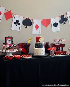 a table topped with lots of cakes and cupcakes next to cards on the wall