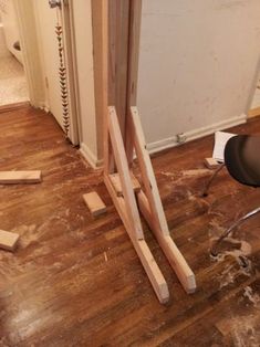 a chair sitting on top of a hard wood floor next to a wooden easel