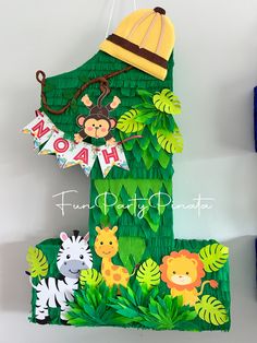 a number made out of green paper with animals on it and a hat hanging from the top