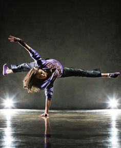 a woman is doing a handstand on the dance floor with her legs spread out