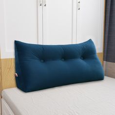 a blue pillow sitting on top of a bed next to a white closet and window