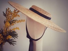 This is a natural straw hat with a shallow crown and a large brim. A classic summer hat perfect for any occasion. The hat is free size and attaches with a discreet millinery elastic, worn around the back of the head. It also has black grosgrain ribbons attached on both sides of the inside belt. These can be tied under the chin, or backside of your neck. Height of the crown:4cm Width of the brim: 13,5 cm Elegant Straw Hat With Flat Crown For Vacation, Elegant Fitted Natural Hat Band, Elegant Natural Boater Hat With Flat Brim, Elegant Adjustable Straw Hat With Flat Crown, Elegant Brimmed Natural Boater Hat, Elegant Natural Brimmed Boater Hat, Classic Fitted Boater Hat For Garden Party, Elegant Wide Brim Straw Boater Hat, Elegant Straw Hat With Flat Crown For Beach