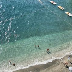 people are swimming in the water near boats