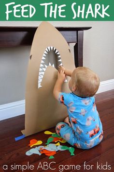 a toddler sitting on the floor playing with a cardboard shark