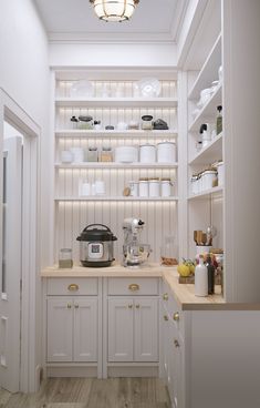 a kitchen with white cupboards and shelves filled with dishes, pots and pans