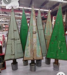 four wooden christmas trees sitting on top of buckets in a room with other items