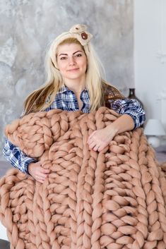 a woman is holding a giant chunky blanket