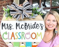 a woman standing in front of a sign that says mrs mcbridge's classroom