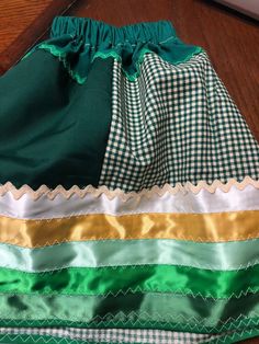 Traditionally made Toddlers Ribbon skirt with green and green gingham cotton fabrics . Width is 52", waist is 21", length is 13".  Blessings! Fitted Green Skirt With Ruffles, Green Tiered Gathered Skirt, Green Gathered Tiered Skirt, Traditional Green Skirt For Spring, Green Cotton Tiered Skirt, Traditional Green Tiered Skirt, Traditional Fitted Green Skirt, Green Cotton Bottoms With Gathered Skirt, Traditional Green Lined Skirt