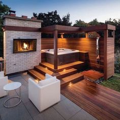 a hot tub sitting on top of a wooden deck next to a white chair and table