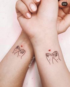 two people holding hands with tattoos on their arms and wrist, one has a heart in the middle