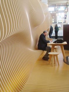 a man sitting at a table in front of a white wall with wavy lines on it