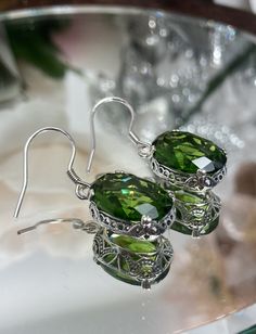 "Simulated Green Peridot Earrings Edward Design#70 Custom Made These are Victorian/Edwardian design earrings in sterling silver set with high-quality simulated Green Peridot gemstones. Each stunning 5ct Green gem is 14mm long (9/16th\") and 10mm in width (3/8th\"). The earrings are 1 1/4th inches long. Notice the beautiful swag/swirl filigree pattern of the setting. A gift box is included and all items are shipped in the gift box for safekeeping. Feel free to ask questions and thanks for looking Ornate Oval Sterling Silver Earrings, Oval Filigree Earrings For Wedding, Oval Earrings With Intricate Design For Anniversary, Ornate Oval Earrings For Anniversary, Green Oval Nickel-free Earrings, Filigree Oval Earrings As Gift, Oval Filigree Earrings As Gift, Green Oval Earrings For Formal Occasions, Oval Wedding Earrings With Intricate Design