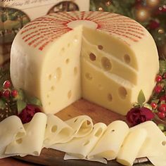 a piece of cheese is cut in half on a cutting board with christmas decorations around it