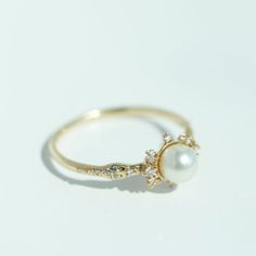 a pearl and diamond ring on a white surface