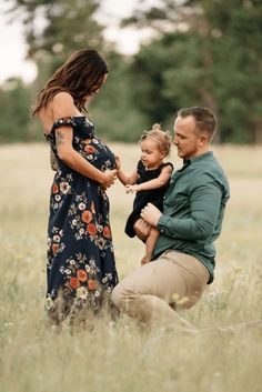 a man, woman and child are sitting in the grass with their arms around each other