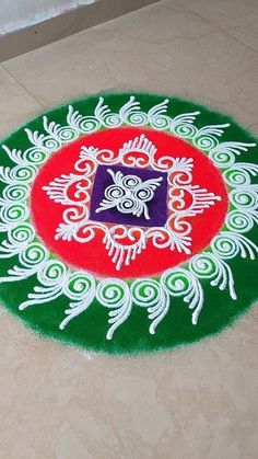 a green and red rug on the floor with an animal in the center surrounded by white swirls