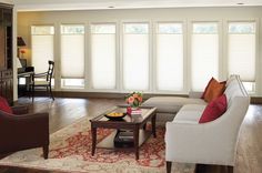 a living room filled with furniture and windows covered in blind shades on the windowsill