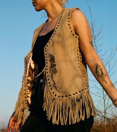 "A smooth suede vest in a natural tan color with fringe trim. Front of vest is embroidered with a beautiful floral motif. Lined in satin and embellished with a border of grommets. Made by Newport News' Jeanology Collection. Size: small-medium, tag reads \"8\"" Bohemian Brown Vest With Fringe, Brown Bohemian Vest With Fringe, Hippie Style Vest For Fall Festival, Brown Bohemian Fringe Vest, Bohemian Brown Fringe Vest, Brown Fringe Vest For Festival, Festival Fringe Brown Vest, Fall Festival Vest With Fringe, Bohemian Fringe Vest For Festivals