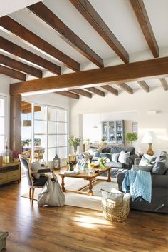 a living room filled with lots of furniture and wooden beams above the couches is a coffee table