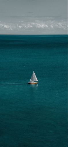 a small sailboat in the middle of an ocean