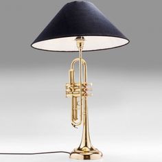 a brass trumpet lamp with a black shade on the base and a white light bulb